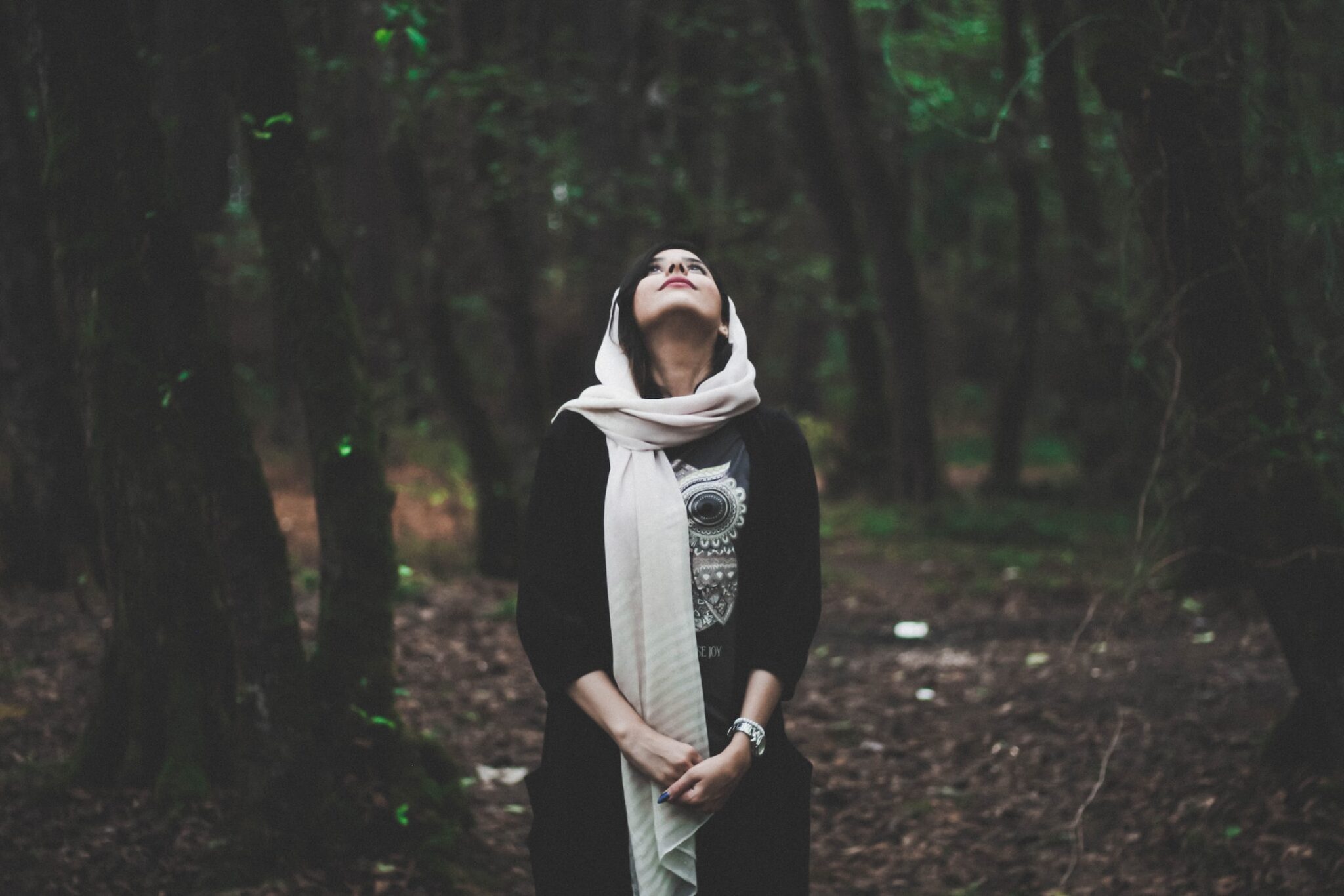 Shallow focus photography of woman in forest looking upward