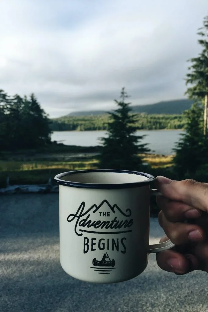 Person holding cup with body of water background