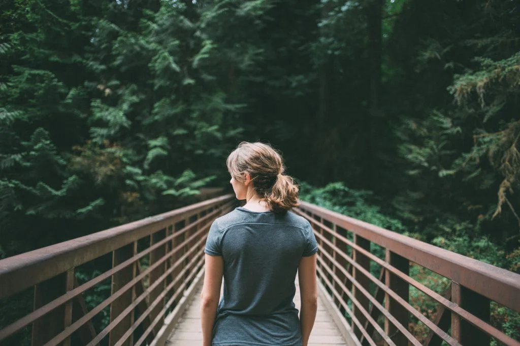 Selective focus photography of woman in black t-shirt standing on bridge